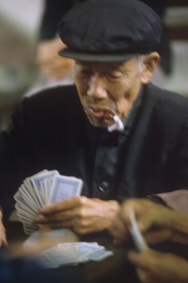 Пожилой китаец за игрой в карты