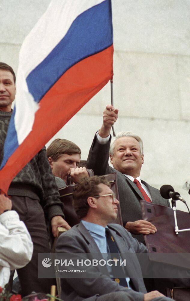 Президент России Б. Н. Ельцин стоит на трибуне с флагом