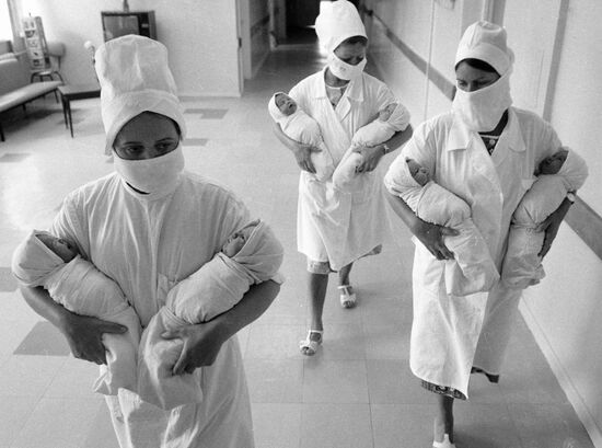 Медицинские сестры несут на руках новорожденных младенцев