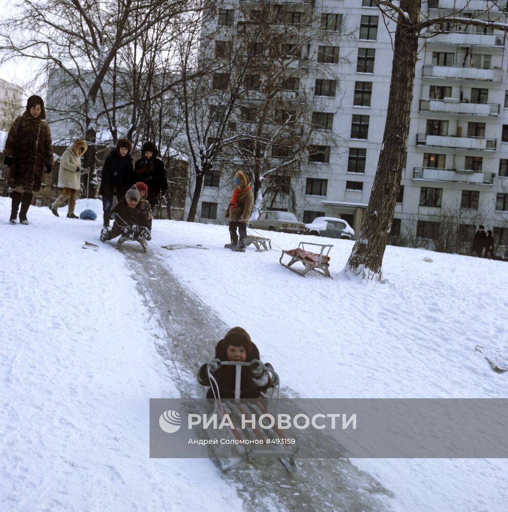 Дети катаются на санках с ледяной горки