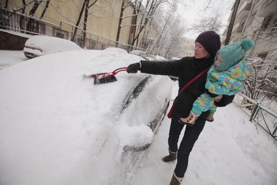 Очистка от снега автомобиля после сильного снегопада в Москве