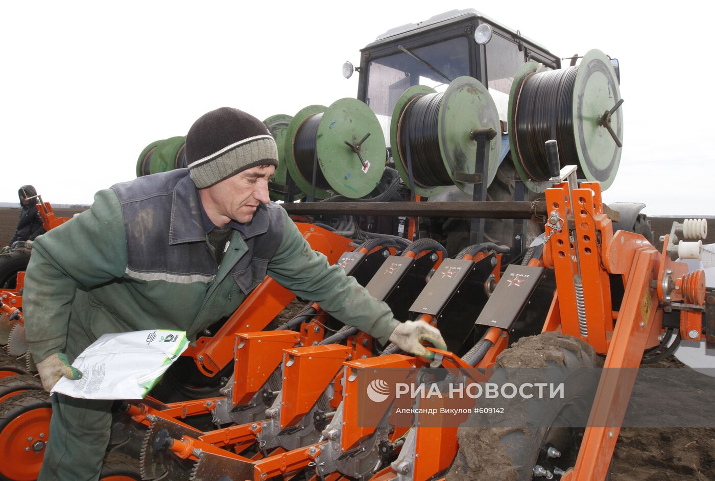 Загрузка семян лука в бункер трактора-сеялки перед посадкой