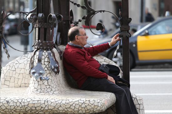 Пенсионер отдыхает на скамейке на улице Пассеч-де-Грасиа