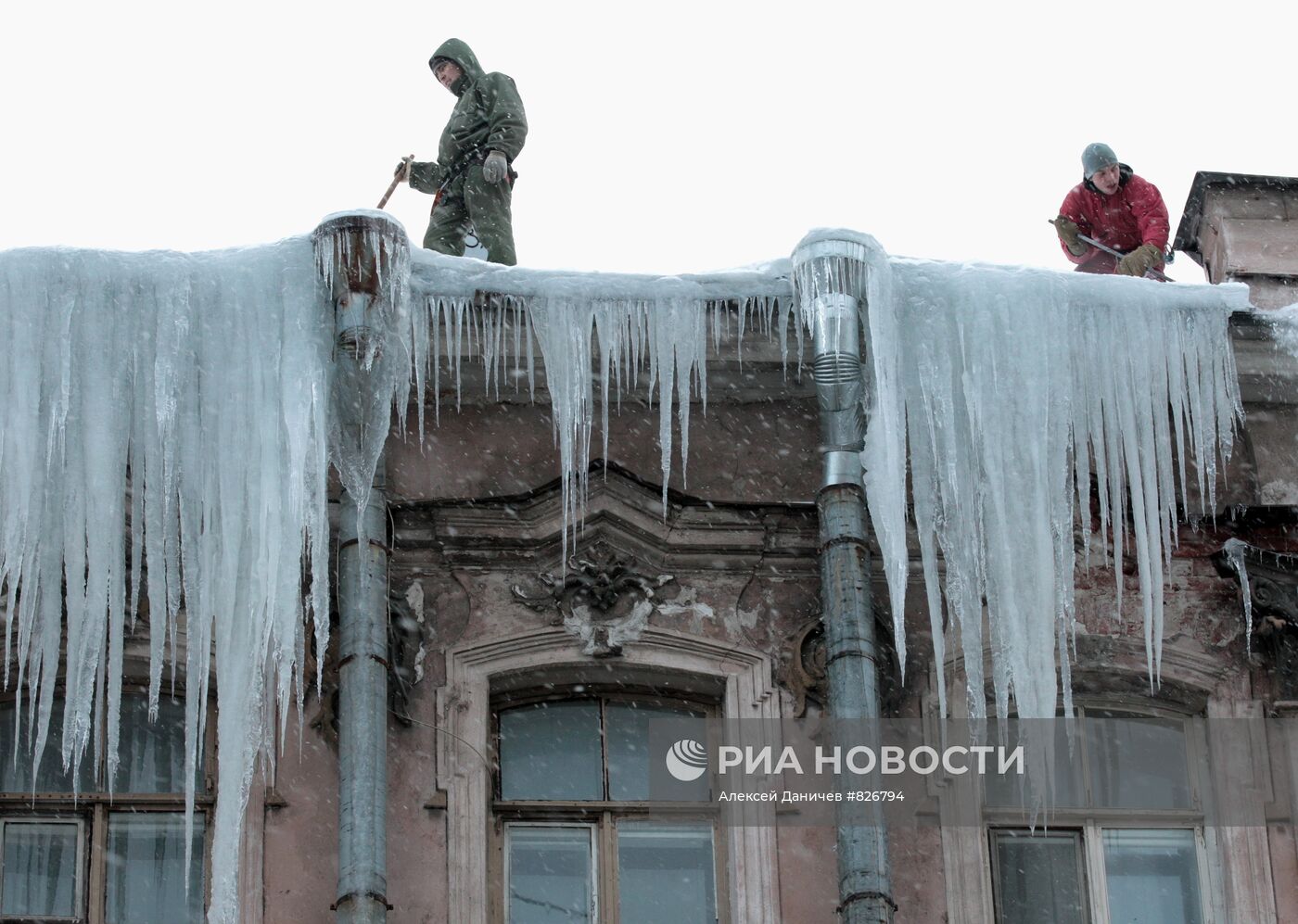 Сотрудники коммунальных служб очищают крыши домов от сосулек