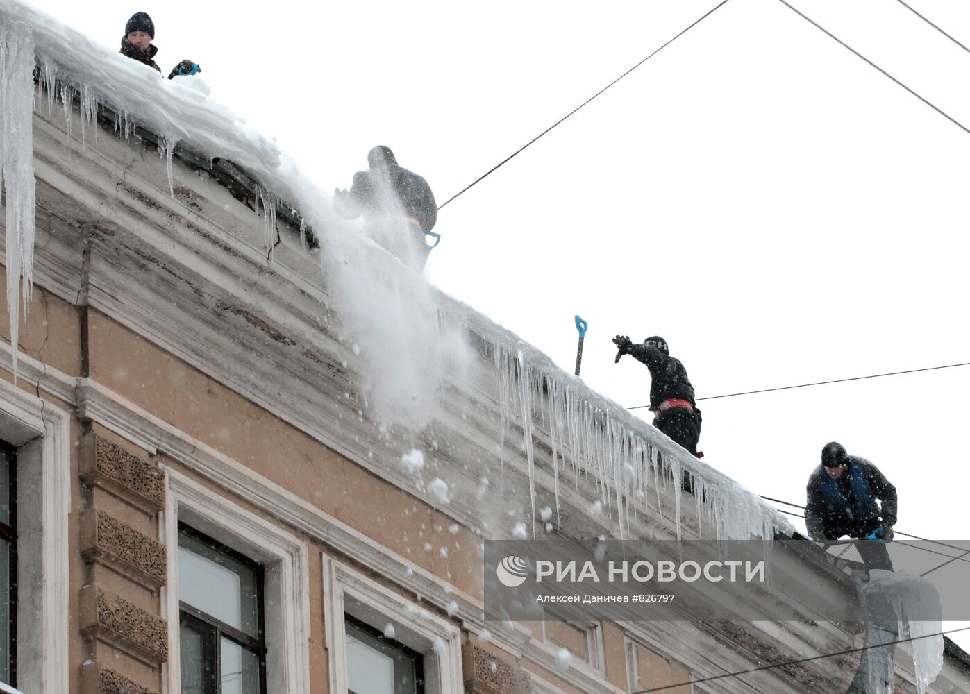 Сотрудники коммунальных служб очищают крыши домов от сосулек