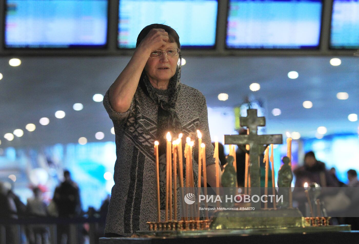 Женщина молится во время панихиды за упокой погибших