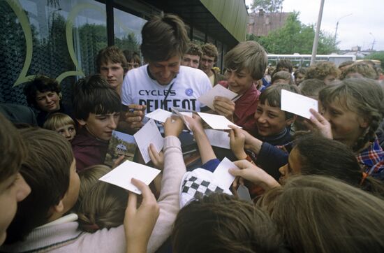 Участник Велопробега мира дает автографы юным болельщикам