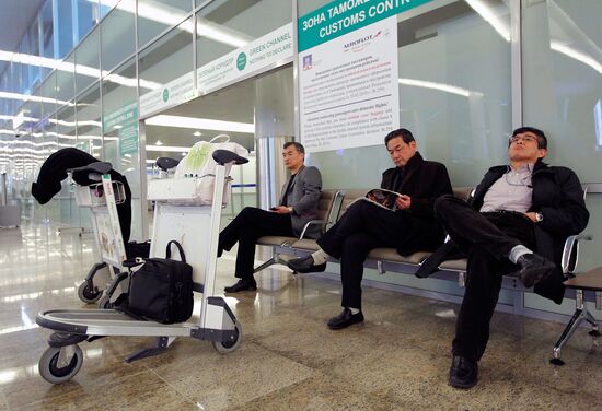 Пассажиры, прибывшие рейсом из Токио, ожидают свой багаж