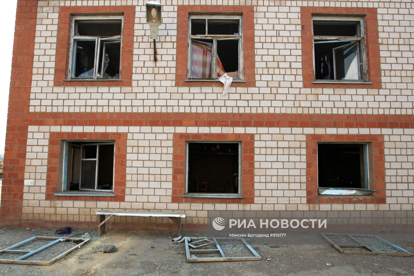 Выбитые взрывом стекла в окнах здания в поселке Постольском