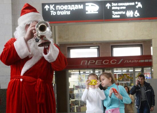 Музыканты в костюмах Дедов Морозов играют для пассажиров московских вокзалов