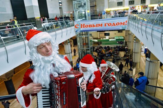 Музыканты в костюмах Дедов Морозов играют для пассажиров московских вокзалов