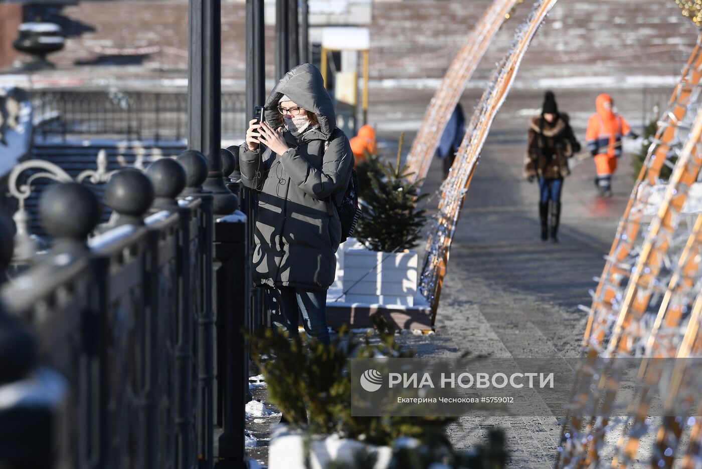 Девушка фотографирует на одной из улиц Москвы. По данным центра погоды "Фобос", температура воздуха в столице на уровне 12-14 градусов ниже нуля. Место: Россия, Москва. Автор: Екатерина Чеснокова/РИА Новости. Мороз в Москве