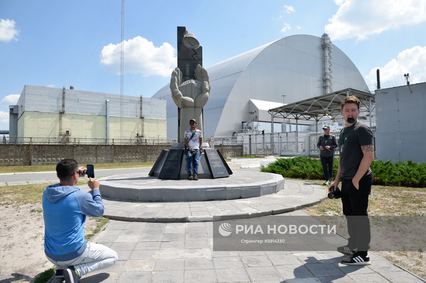 Туристы фотографируются возле памятника ликвидаторам аварии на Чернобыльской атомной электростанции (ЧАЭС) имени Владимира Ильича Ленина во время экскурсии в зону отчуждения в городе Чернобыль. Место: Украина, Киевская область, Припять. Автор: Стрингер/РИА Новости. Туристический "бум" в Чернобыльской зоне отчуждения