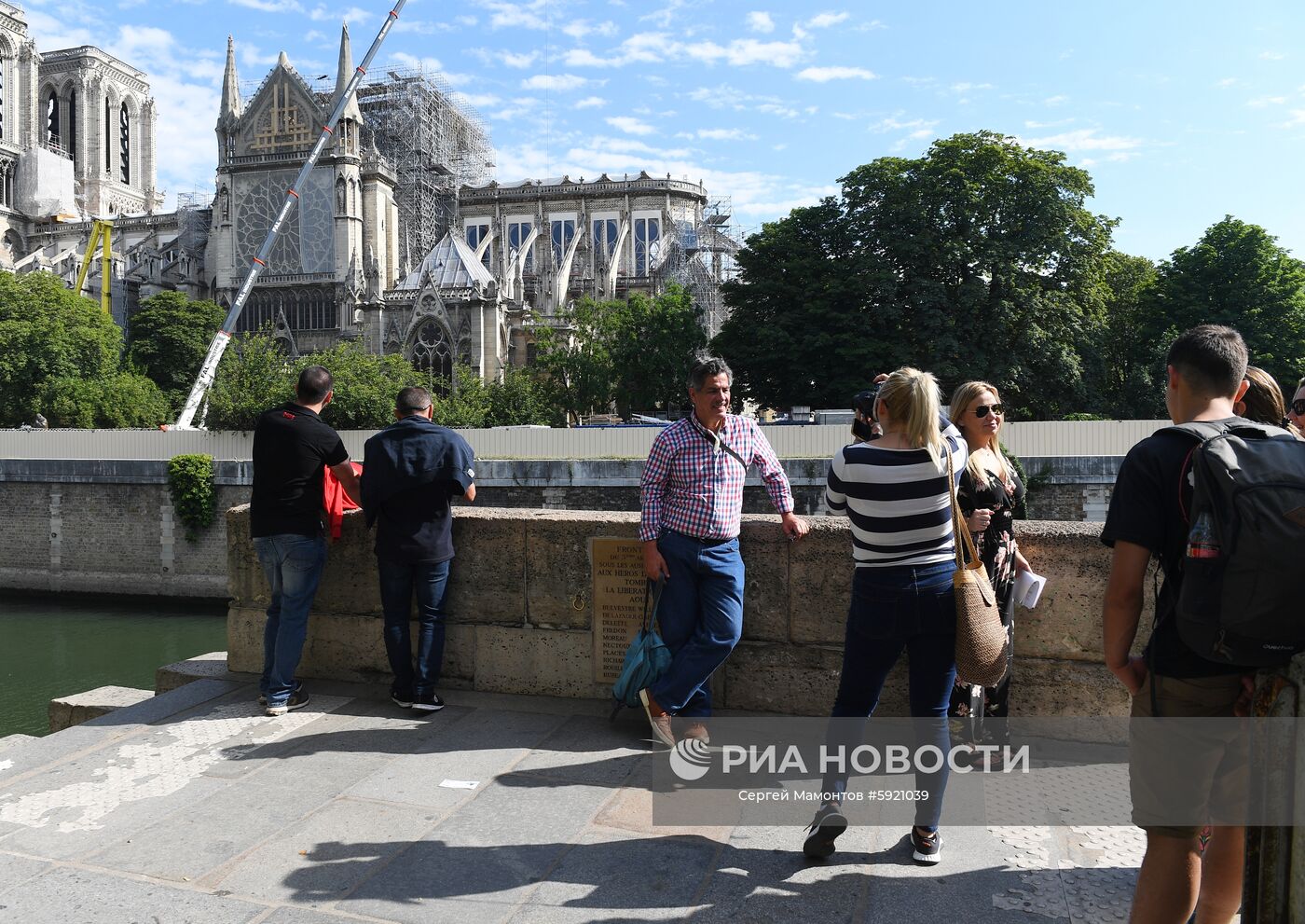 Туристы на набережной Сены у Собора Парижской Богоматери (Notre Dame de Paris) в Париже. На дальнем плане Собор Парижской Богоматери (Notre Dame de Paris) в Париже. В Соборе проводятся восстановительные работы после пожара, случившегося 15 апреля 2019 года. Место: Франция, Париж. Автор: Сергей Мамонтов/РИА Новости. Города мира. Париж