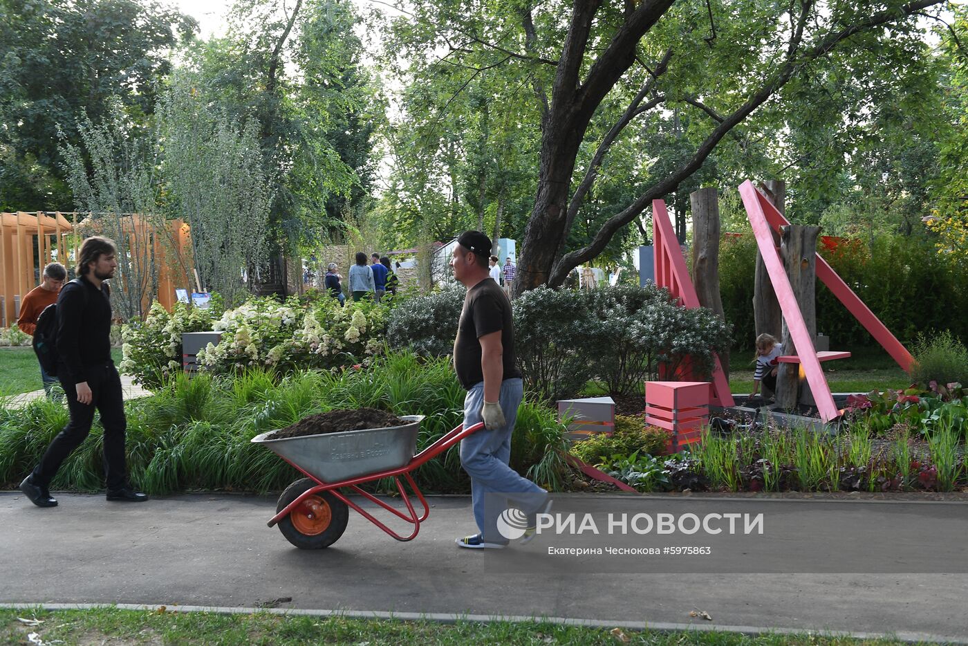 Посетители и работник на VI Московском международном фестивале ландшафтного искусства, садоводства и питомниководства "Сады и люди" на тему "Пятый элемент" в Северном сквере на ВДНХ. Место: Россия, Москва. Автор: Екатерина Чеснокова/РИА Новости. VI фестиваль "Сады и люди" на ВДНХ