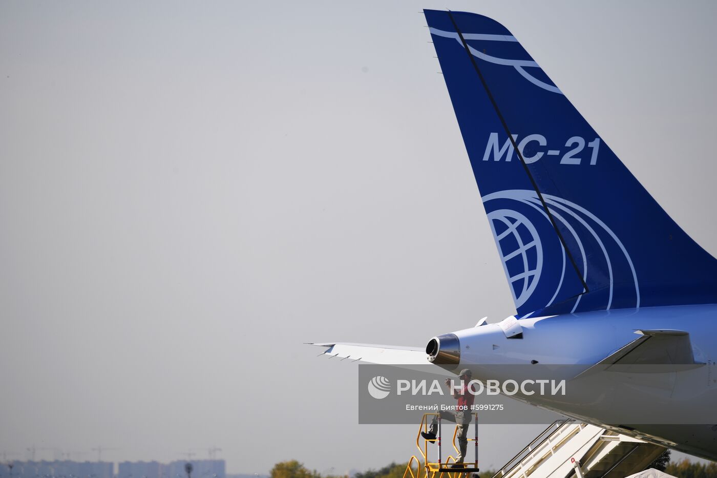 Мужчина фотографирует самолеты на Международном авиационно-космическом салоне МАКС-2019 в подмосковном Жуковском. Справа: хвост пассажирского самолёта МС-21-300. Место: Россия, Московская область, Жуковский. Автор: Евгений Биятов/РИА Новости. Международный авиационно-космический салон МАКС-2019. День четвертый