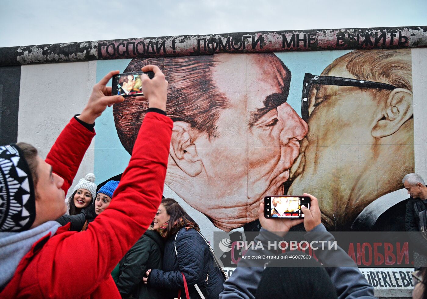 Люди у фрагмента Берлинской стены (East-Side Gallery) на Мюленштрассе с произведением Дмитрия Врубеля "Господи! Помоги мне выжить среди этой смертной любви" или "Братский поцелуй" (поцелуй Брежнева и Хонеккера). В Берлине проходят мероприятия по случаю 30-летней годовщины падения Берлинской стены, ознаменовавшего воссоединение населения ФРГ и ГДР. Место: Германия, Берлин. Автор: Алексей Витвицкий/РИА Новости. Мероприятия по случаю 30-летней годовщины падения Берлинской стены