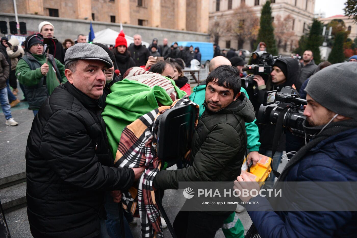 Одного из участников акции протеста перед зданием парламента в Тбилиси несут к машине скорой помощи. Акции протеста в Тбилиси начались после того, как парламент Грузии не принял поправки в конституцию по изменению избирательной системы. Отклоненные поправки предполагали проведение парламентских выборов в 2020 году по пропорциональной системе (вместо смешанной) и при нулевом избирательном барьере. Место: Грузия, Тбилиси. Автор: Александр Шламов/Sputnik/РИА Новости. Акция протеста в Тбилиси
