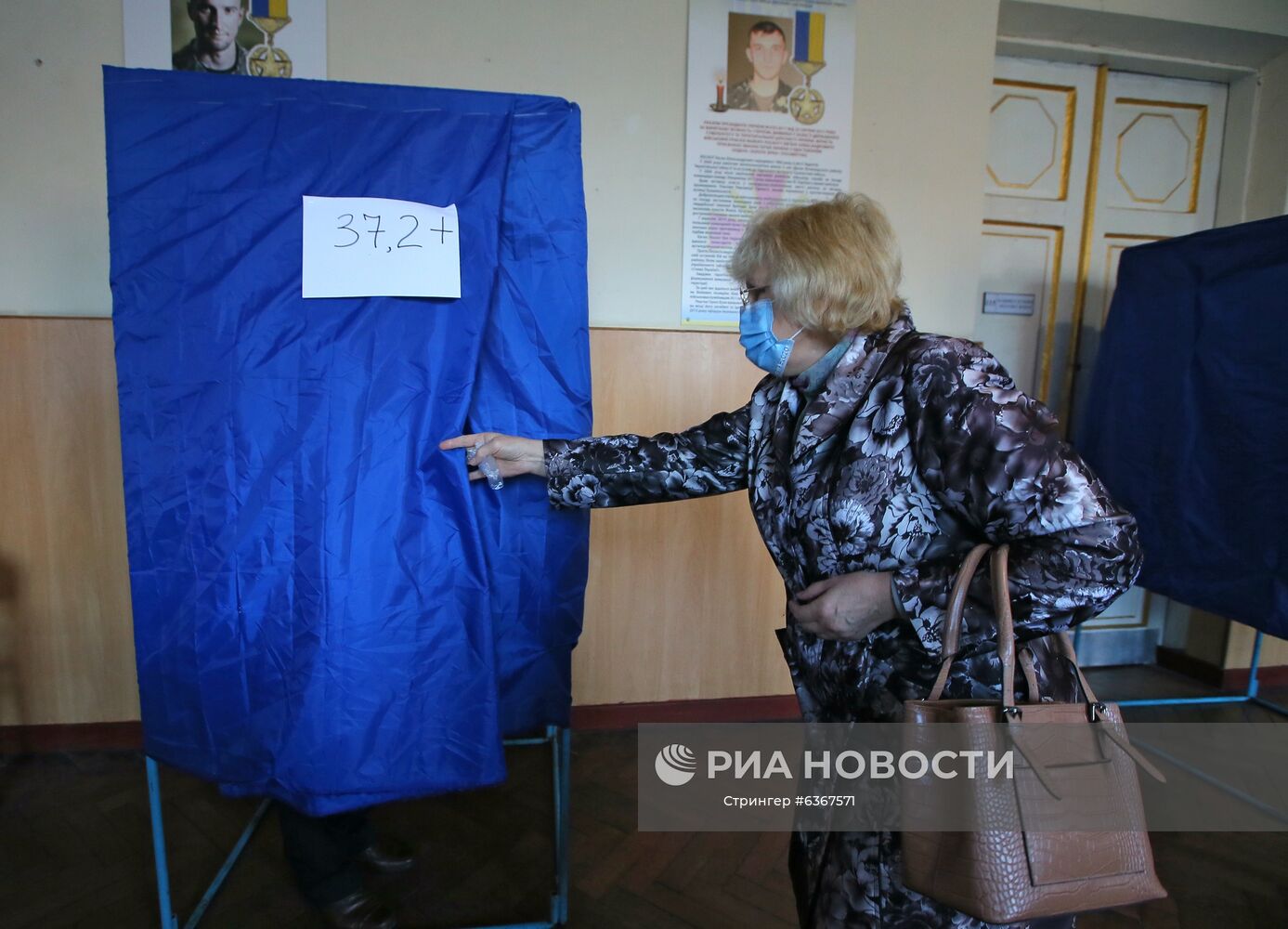 Женщина возле кабинки для голосования для людей с повышенной температурой тела на одном из избирательных участков в Киеве. Место: Украина, Киев. Автор: Стрингер/РИА Новости. Региональные выборы на Украине