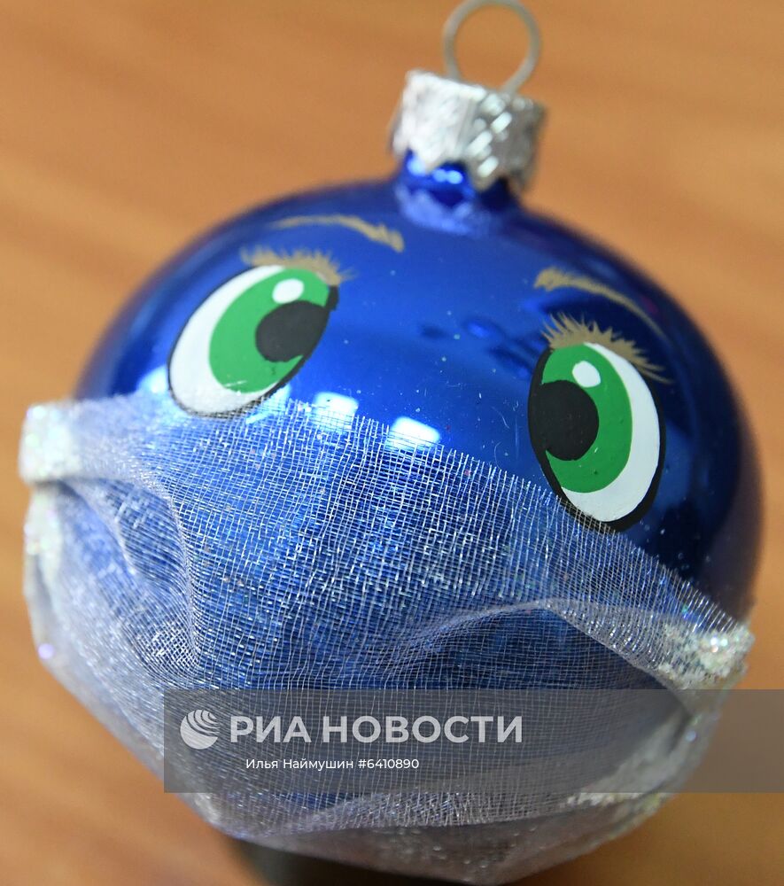 Стеклянный новогодний шар, расписанный вручную, на фабрике игрушек "Бирюсинка" в Красноярске. Повышенным спросом у покупателей в этом году пользуются ёлочные украшения с изображением защитных лицевых масок. Место: Россия, Красноярск. Автор: Илья Наймушин/РИА Новости. Красноярская фабрика игрушек выпустила елочные шары в масках от COVID-19