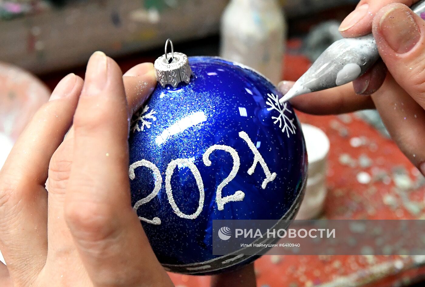 Художница расписывает стеклянный новогодний шар на фабрике игрушек "Бирюсинка" в Красноярске. Повышенным спросом у покупателей в этом году пользуются ёлочные украшения с изображением защитных лицевых масок. Место: Россия, Красноярск. Автор: Илья Наймушин/РИА Новости. Красноярская фабрика игрушек выпустила елочные шары в масках от COVID-19