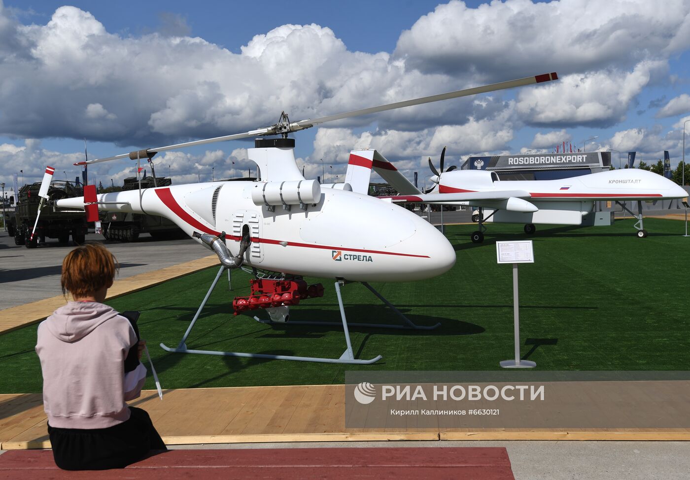 Беспилотный летательный аппарат вертолетного типа компании "Стрела", представленный на открытой экспозиционной площадке Конгрессно-выставочного центра "Патриот" на Международном форуме "АРМИЯ-2021". На втором плане -тяжелый беспилотный летательный аппарат радиолокационного дозора "Гелиос-РЛД" компании "Кронштадт". Место: Россия, Московская область. Автор: Кирилл Каллиников/РИА Новости. Международный форум "АРМИЯ-2021". "Танковый биатлон"