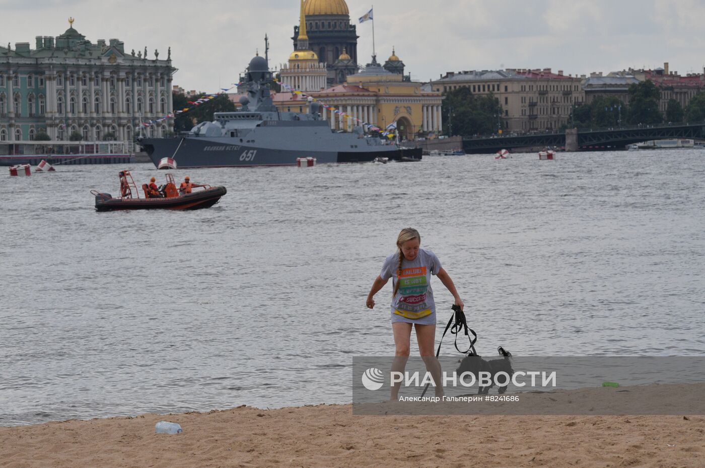 Женщина гуляет с собакой на пляже у Петропавловской крепости в Санкт-Петербурге. На дальнем плане: малый ракетный корабль "Великий Устюг" проекта 21631 "Буян-М" в акватории реки Невы после репетиции морского парада ко Дню ВМФ в Санкт-Петербурге. Место: Россия, Санкт-Петербург. Автор: Александр Гальперин/РИА Новости. Репетиция парада ко Дню ВМФ в Санкт-Петербурге