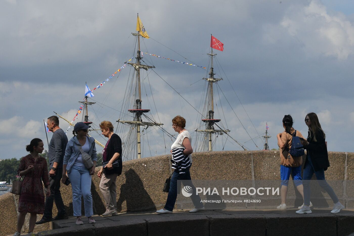 Прохожие на мосту в Санкт-Петербурге. На втором плане: мачты парусного линейного корабля "Полтава", который остался в акватории реки Невы после репетиции морского парада ко Дню ВМФ в Санкт-Петербурге. Место: Россия, Санкт-Петербург. Автор: Александр Гальперин/РИА Новости. Репетиция парада ко Дню ВМФ в Санкт-Петербурге